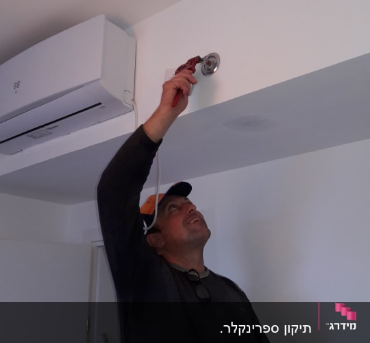 אדם משתמש במפתח צינורות לתיקון צינור
